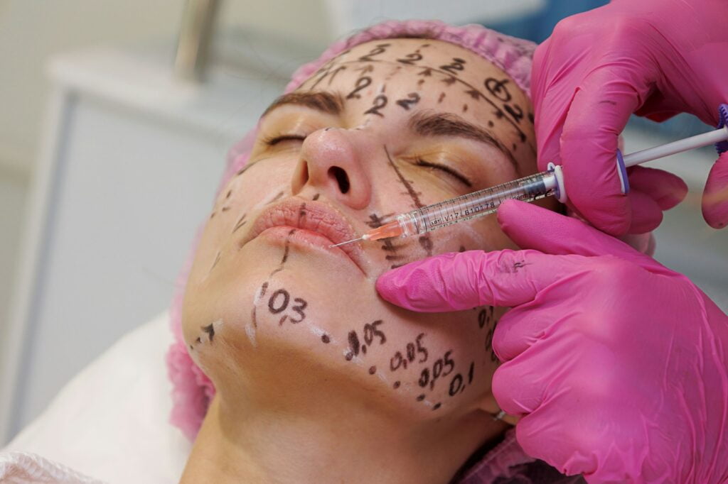 Woman doing cosmetology procedure, hyaluron injection. Woman face lift