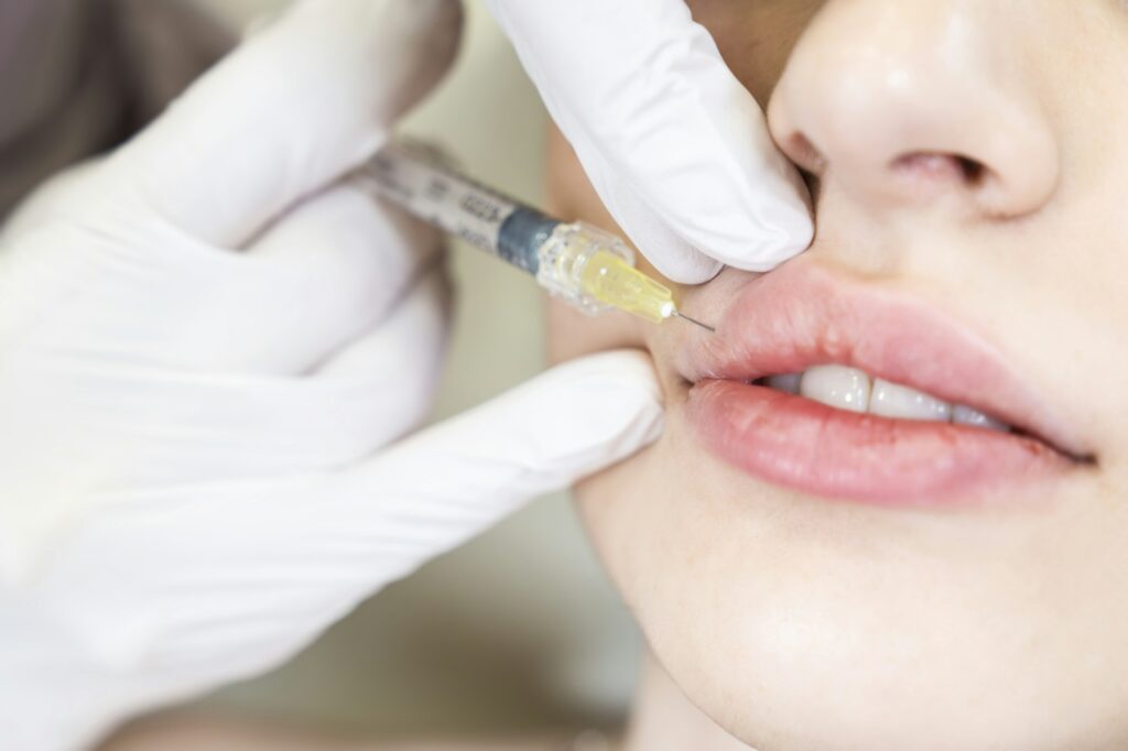 Young woman gets injection of botox in her lips. Woman in beauty salon. plastic surgery clinic.